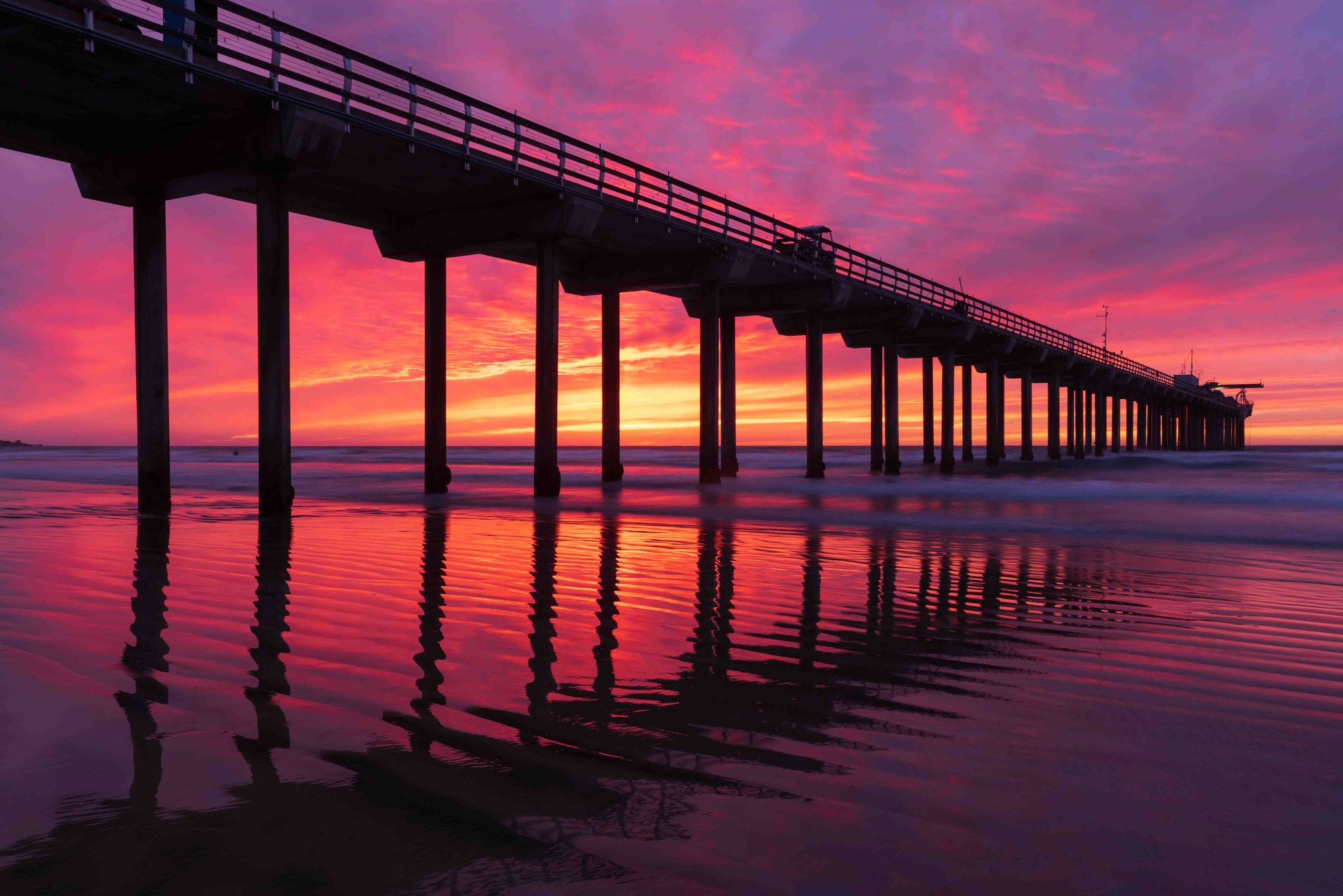 Long-exposure seascape at a San Diego pier — smooth water, dramatic sky, the Pacific at its most cinematic